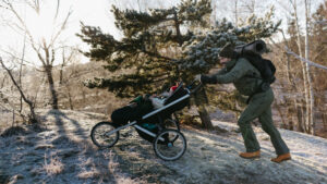 Mann i vinterlandskap skyver en barnevogn opp en bakke